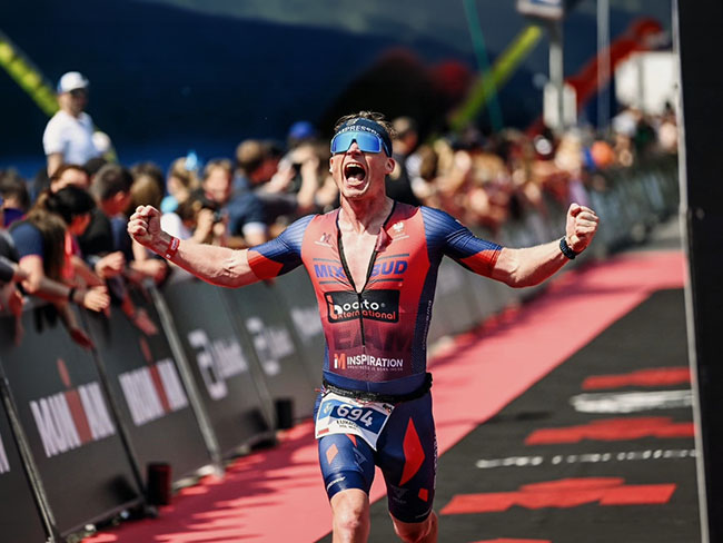 Triathlonista świętuje ukończenie IRONMANA z uniesionymi rękami - plan treningowy IRONMAN IM Inspiration