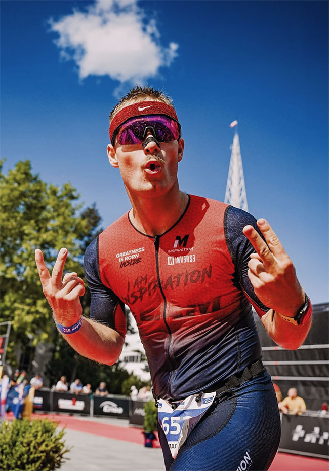 Triathlonista przekracza linię mety w stroju startowym I AM INSPIRATION - plan treningowy triathlonowy IM Inspiration
