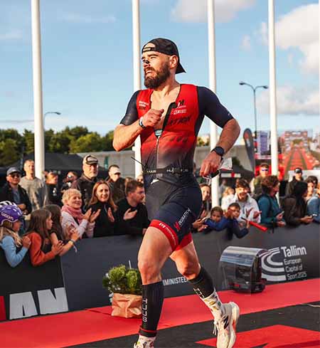 Biegacz kończy biegową część maratonu IRONMANA w słonecznej aurze - plan treningowy maratonu IM Inspiration